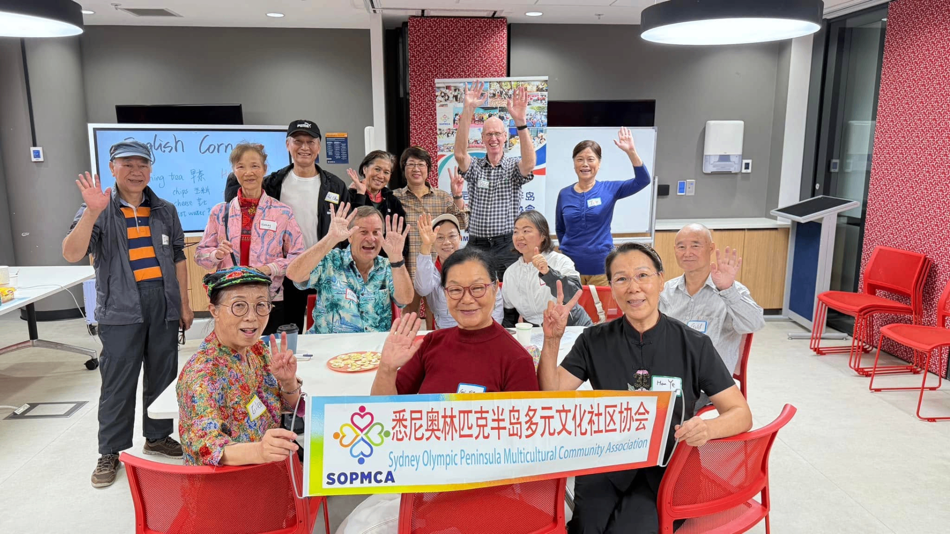SOPMCA English Corner group at Wentworth Point — multicultural community members holding the SOPMCA banner